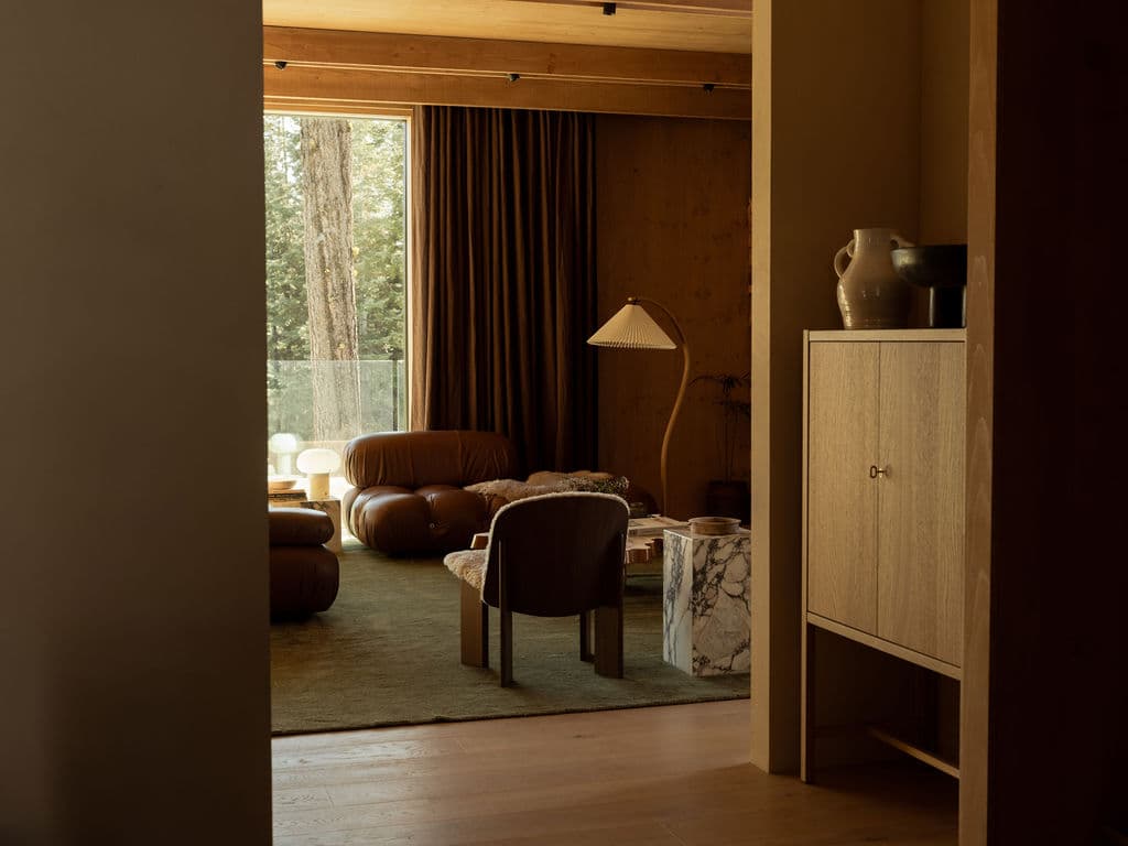 Living room glimpse through doorway with Camaleonda sofa, bentwood floor lamp and marble coffee table