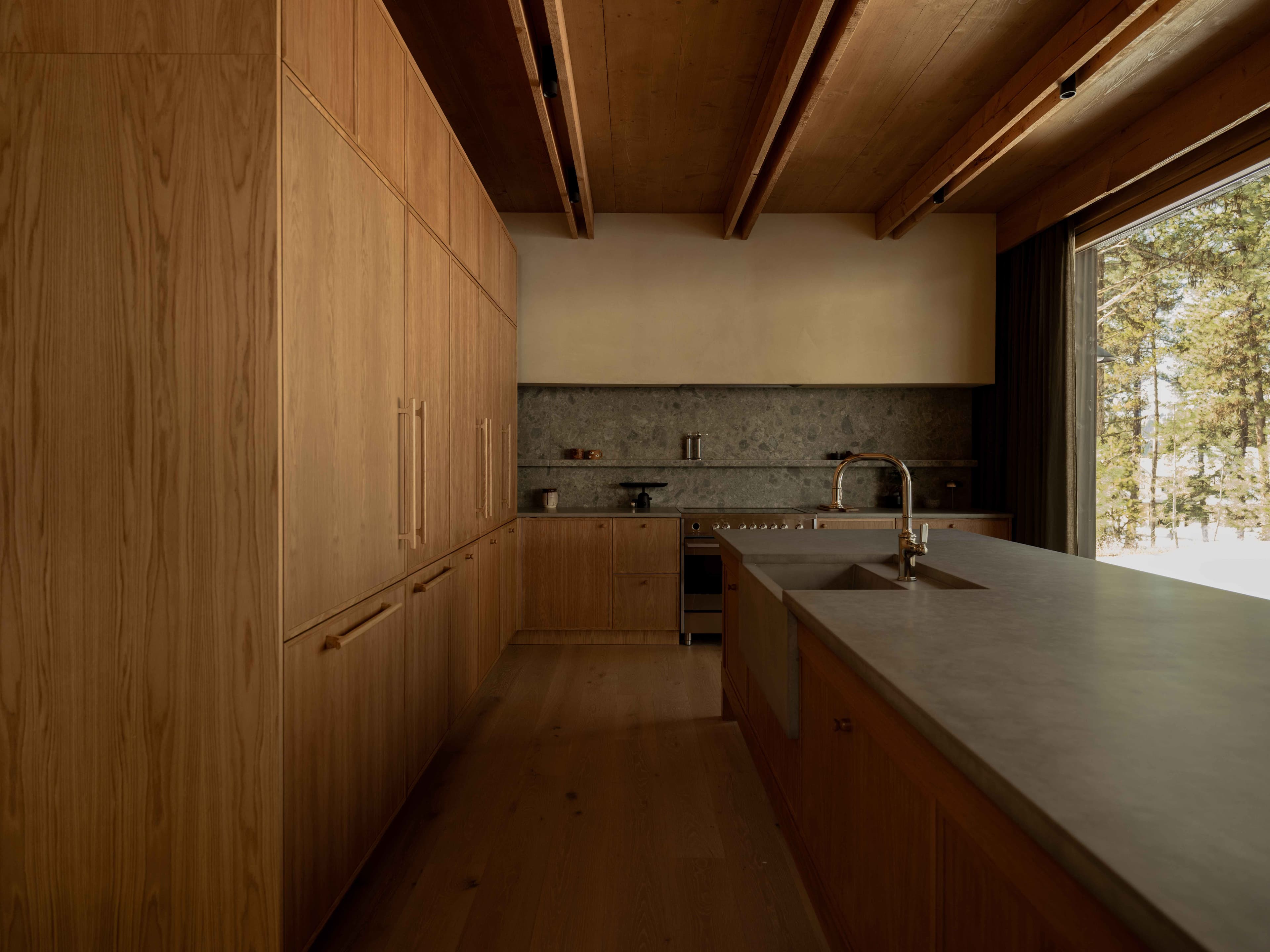 Full kitchen with custom oak cabinetry, concrete island, stone backsplash and exposed timber ceiling