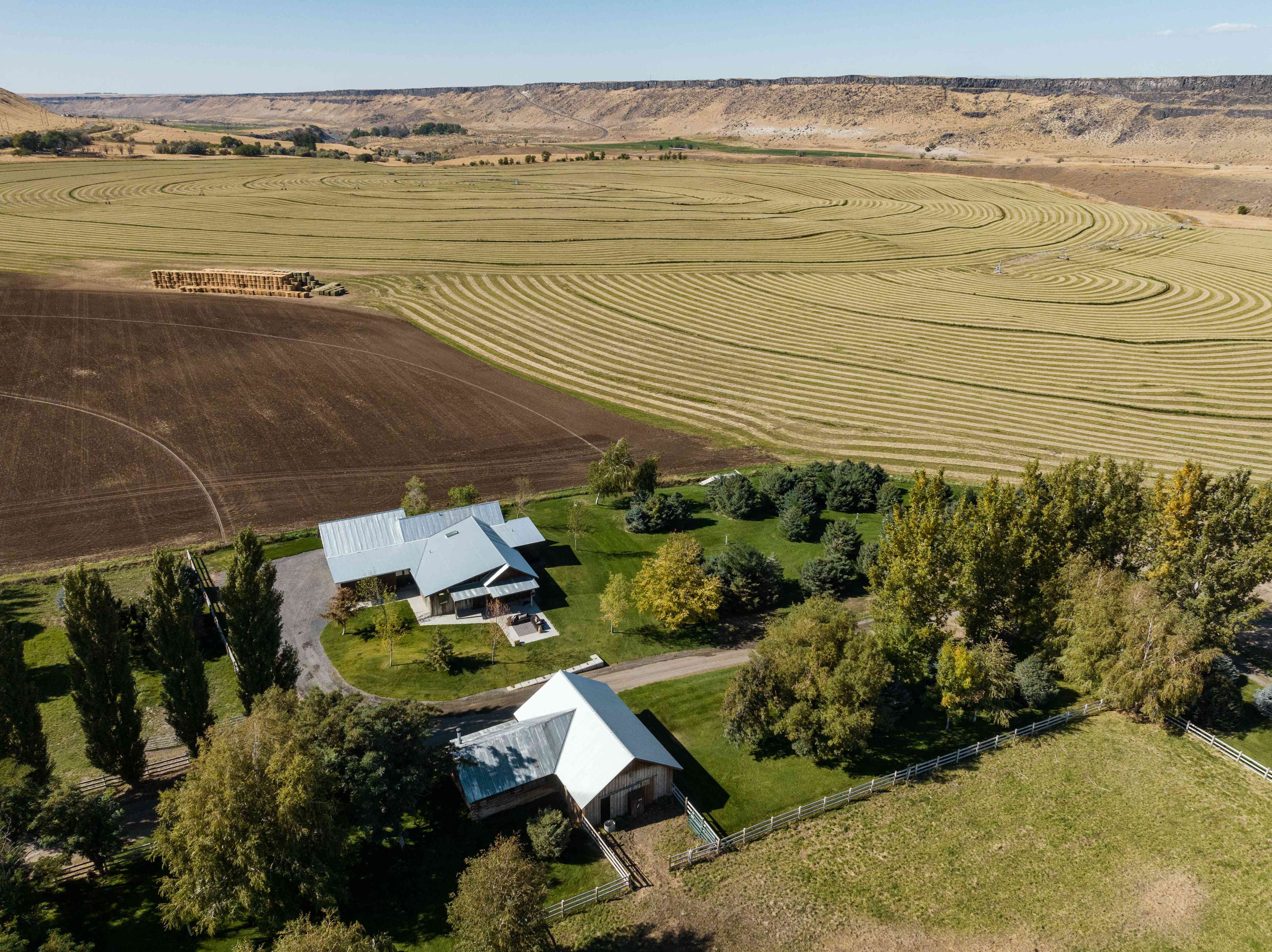 Aerial view of Double R 2.0 property showing main house and barn surrounded by trees with agricultural fields and canyon beyond